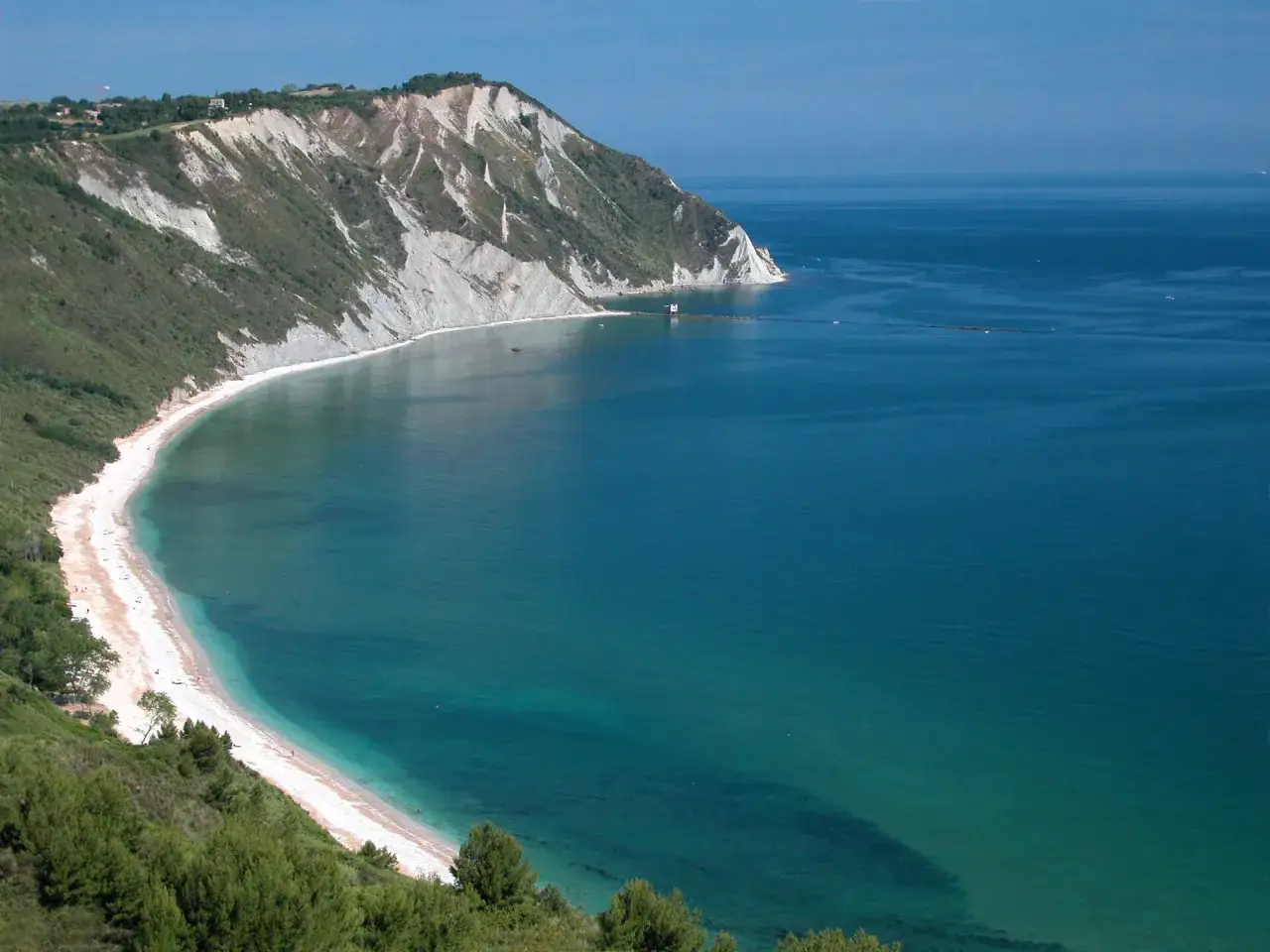 La spiaggia di Ancona si estende lungo una costa rocciosa con acque cristalline.