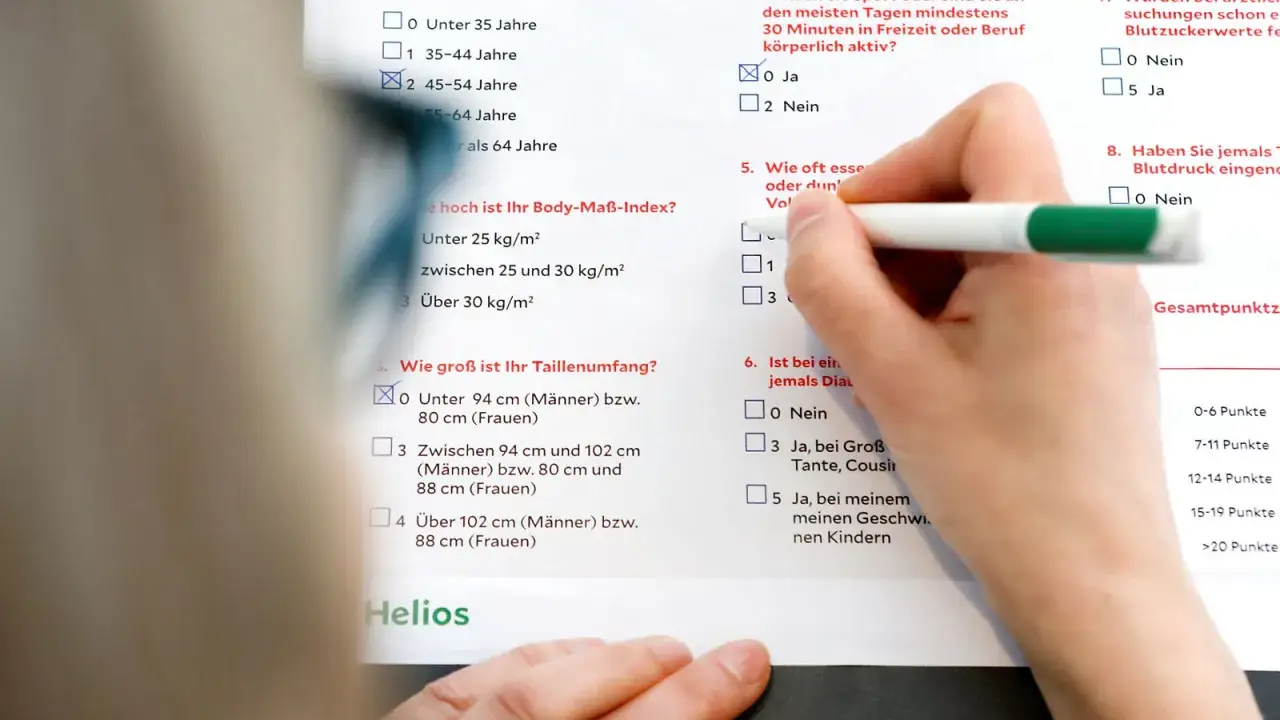 Hand f&uuml;llt Fragebogen aus, der Fragen zu Lebensstil und Risikofaktoren f&uuml;r Diabetes enth&auml;lt. Eine Diabetes Blutwerte Tabelle ist im Hintergrund zu sehen.