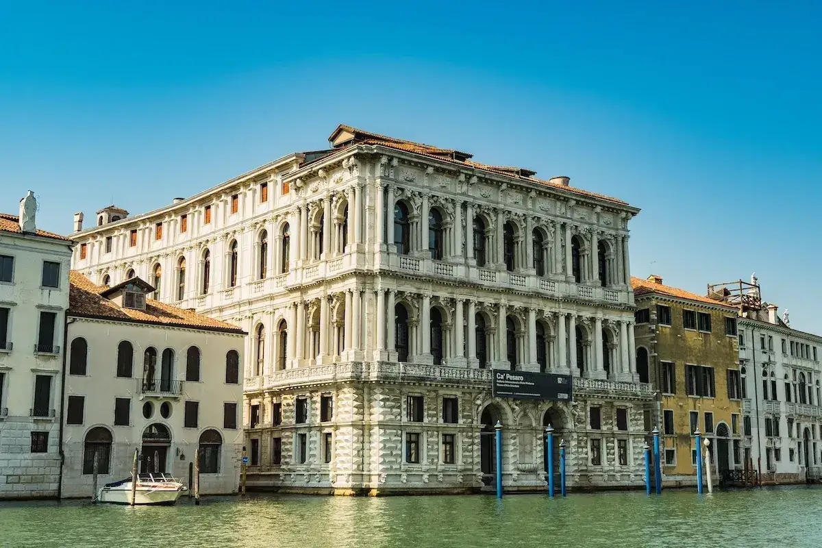 Palazzo Ca' Pesaro a Venezia, un maestoso edificio storico affacciato sul Canal Grande, con un'imbarcazione ormeggiata.