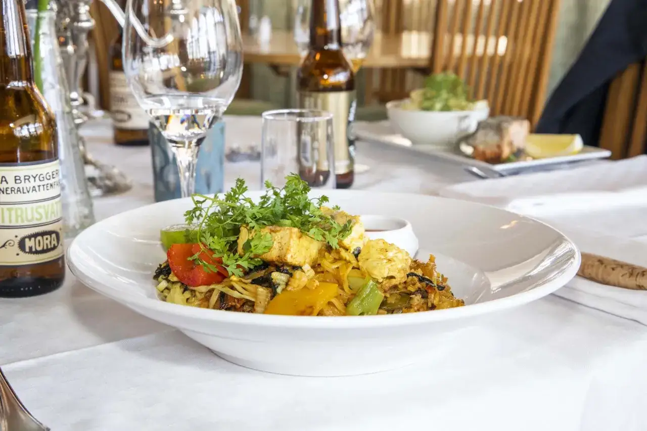 En vacker m&aring;ltid med fisk och gr&ouml;nsaker serveras p&aring; en tallrik. En flaska Mora Citronvatten st&aring;r bredvid. En h&auml;rlig upplevelse p&aring; Moraparken restaurang.