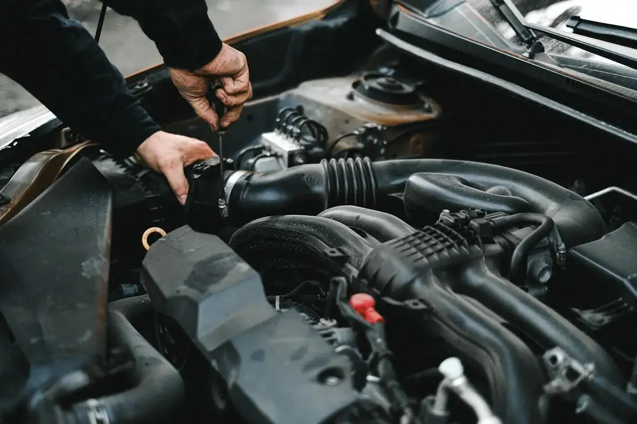 Mechanik dokręca śrubę przy silniku, sprawdzając poduszki silnika.