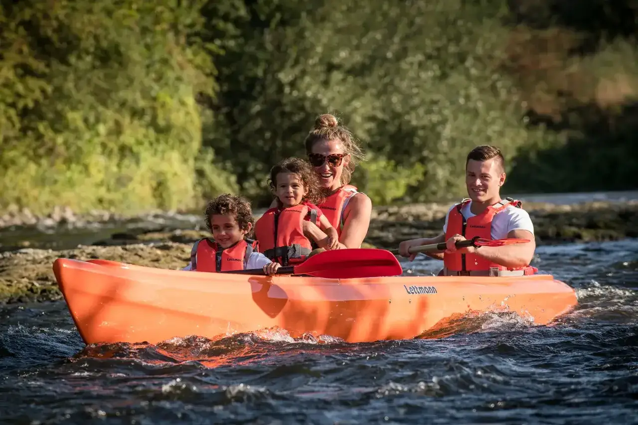 Familie genießt eine Fahrt im orangefarbenen Kanu auf der Lippe.