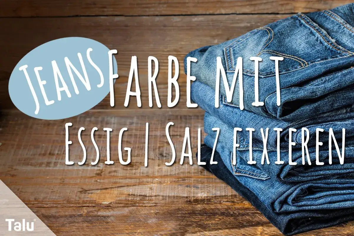 Neue Jeans waschen und die Farbe mit Essig fixieren. Ein Stapel Jeans auf Holzhintergrund.