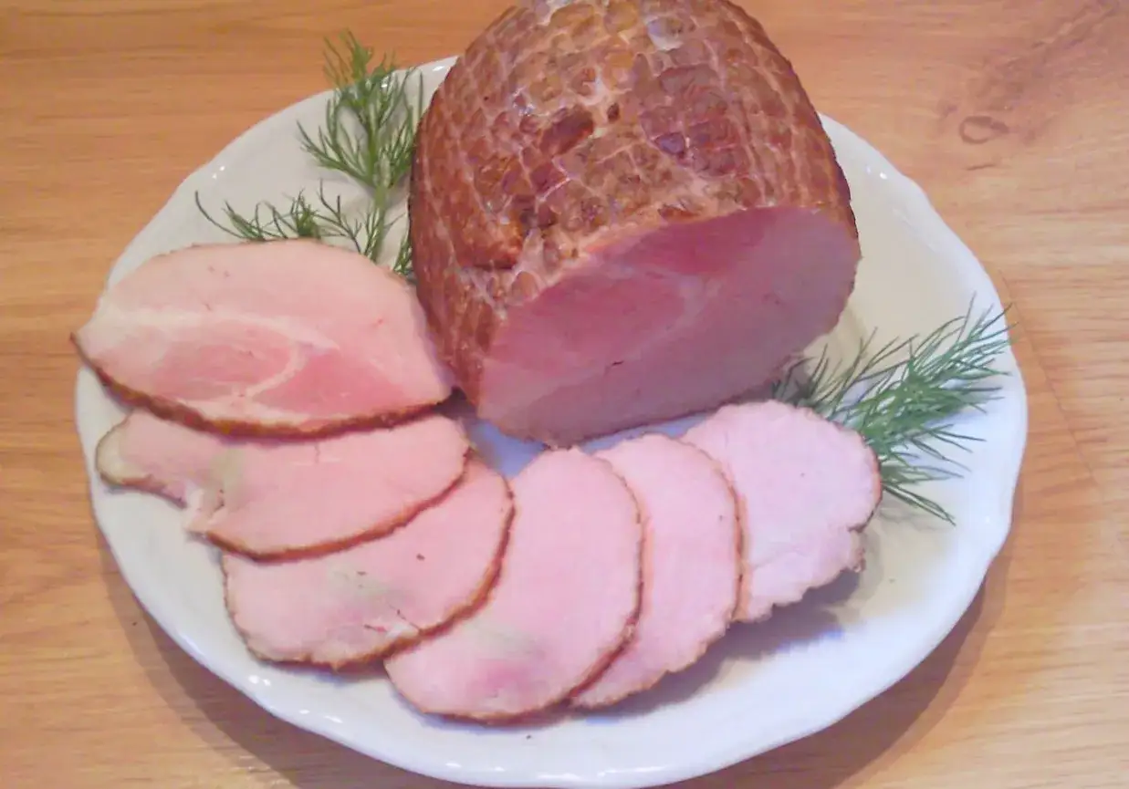 Wędzenie szynki bez parzenia. Aromatyczna, soczysta szynka pokrojona w plastry, ozdobiona gałązkami koperku.