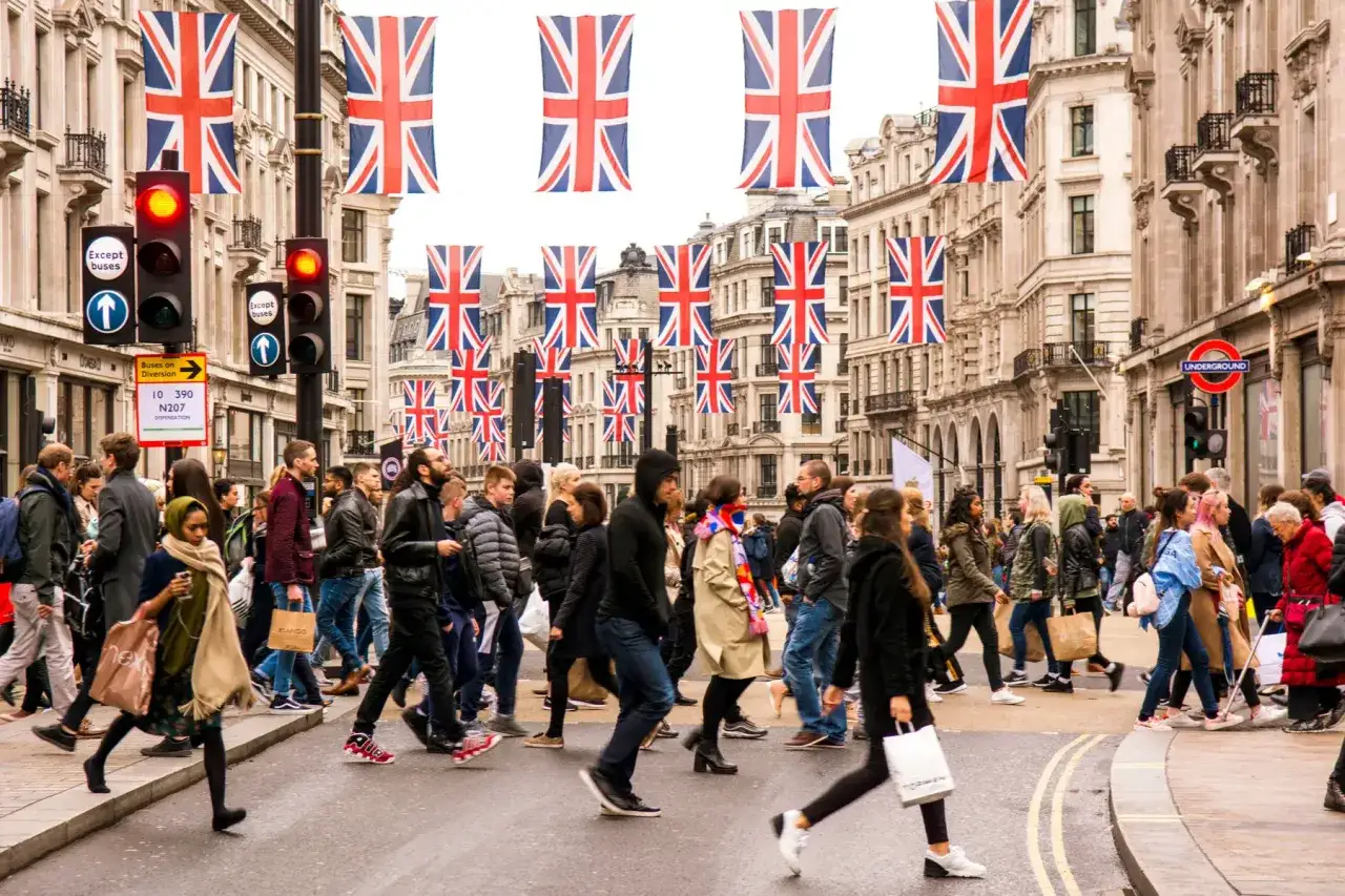 Gente cruza una calle adornada con banderas del Reino Unido, celebrando las tradiciones de reino unido.