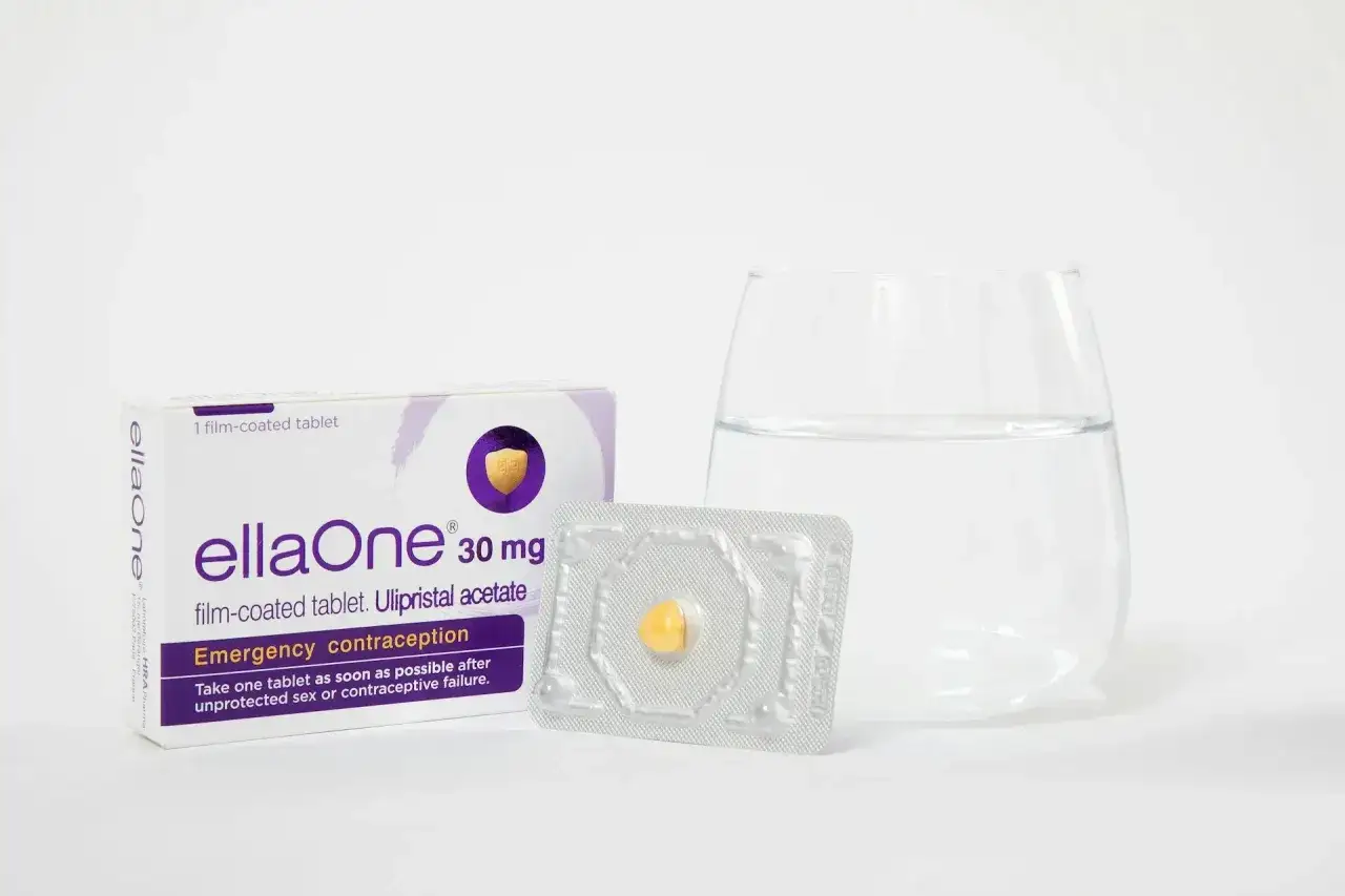 EllaOne – tabletka antykoncepcji awaryjnej, pomocna po seksie bez zabezpieczenia. Obok opakowanie, blister z tabletką i szklanka wody.