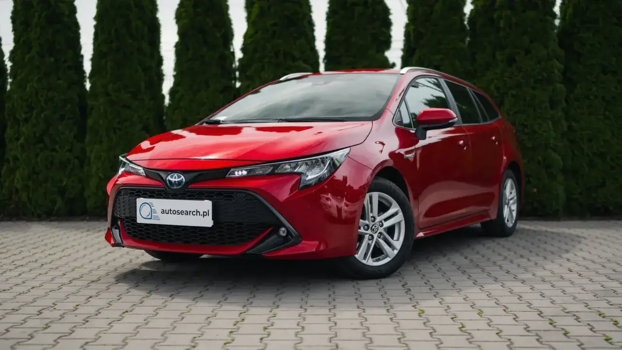 Czerwona Toyota Corolla 2.0 Hybrid na tle żywopłotu. Sprawdź dane techniczne tego modelu.