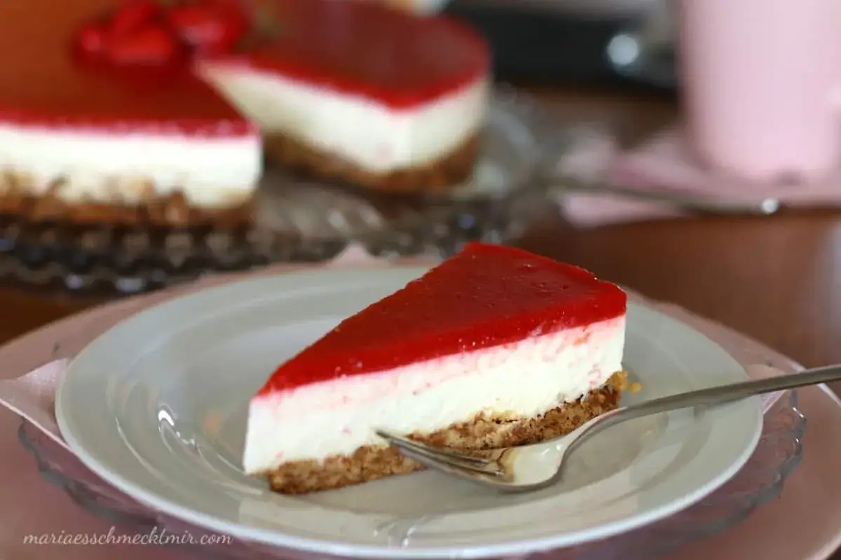 Ein Stück cremiger Erdbeer-Cheesecake mit fruchtiger Erdbeersauce auf einem Keksboden, bereit zum Genießen.