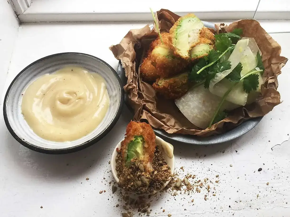 Krispigt friterad avokado med en krämig dipp och fräscha grönsaker. En perfekt snack!