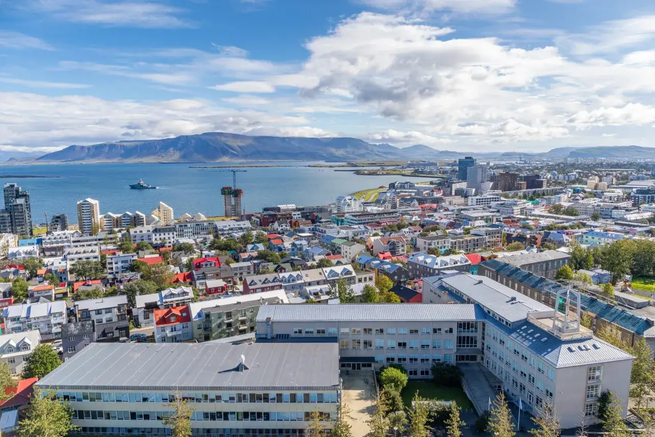 Widok na Reykjavík, stolicę Islandii, z kolorowymi domami, nowoczesnymi budynkami i zatoką w tle.