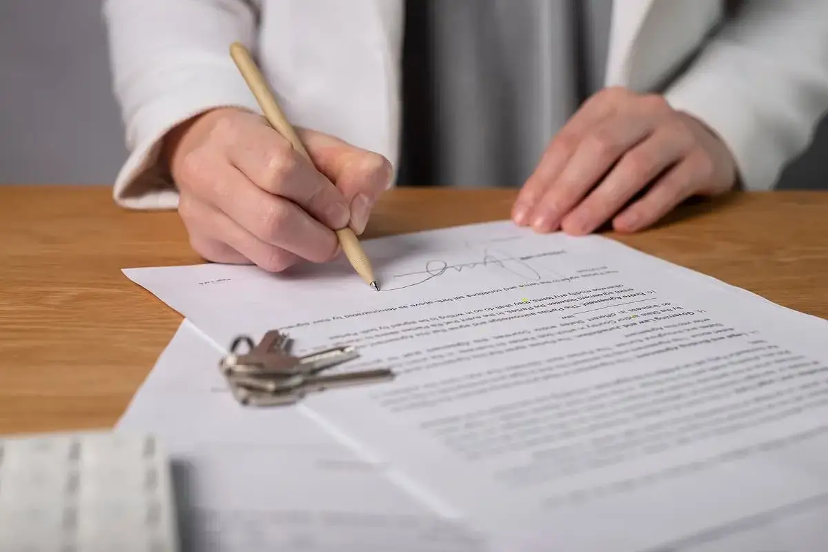 Firma de escritura pública de vivienda. Unas llaves y un contrato sobre una mesa de madera.
