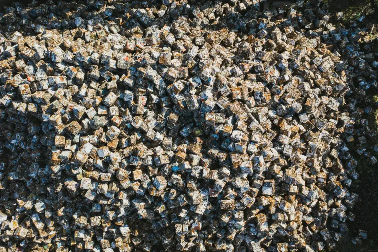 Góra sprasowanych kostek złomu, gotowa do recyklingu metalu. Każda kostka to historia dawnych przedmiotów, które zyskają nowe życie.