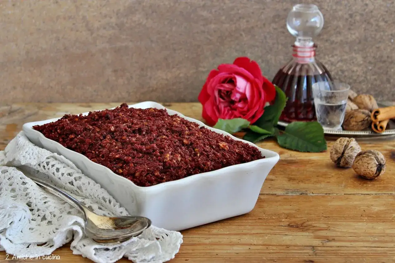 Un dolce rosso intenso, perfetto per scoprire cosa mangiare in Umbria. Noci, cannella e una rosa rossa completano la scena.