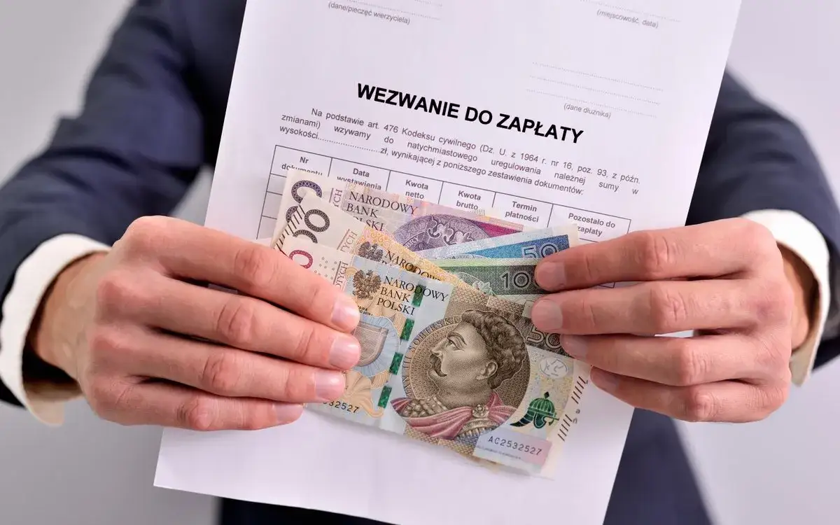 wezwanie do zapłaty leżące na stole obok portfela