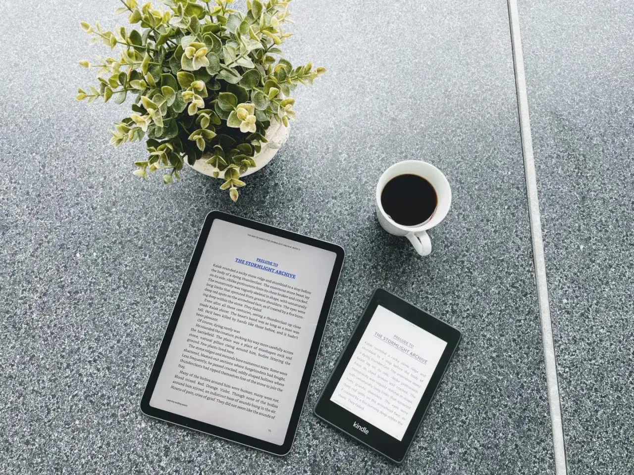 Une tasse de café, une plante verte et un appareil Nextory Kindle à côté d'une tablette affichant un livre.
