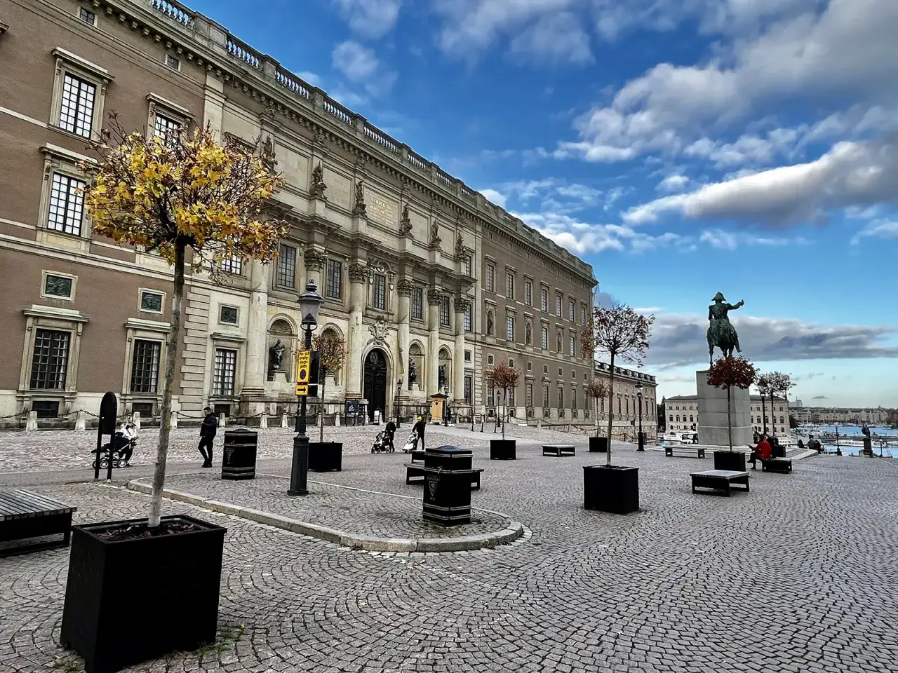 Stora torget framf&ouml;r slottet i Gamla Stan, Stockholm, med en ryttarstaty och h&ouml;sttr&auml;d under en molnig himmel.