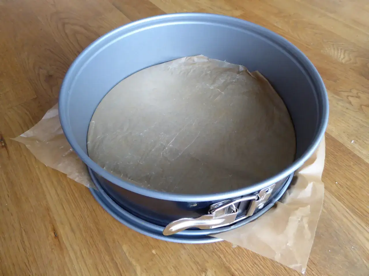 En springform med bakpl&aring;tspapper redo f&ouml;r en saftig sockerkaka.