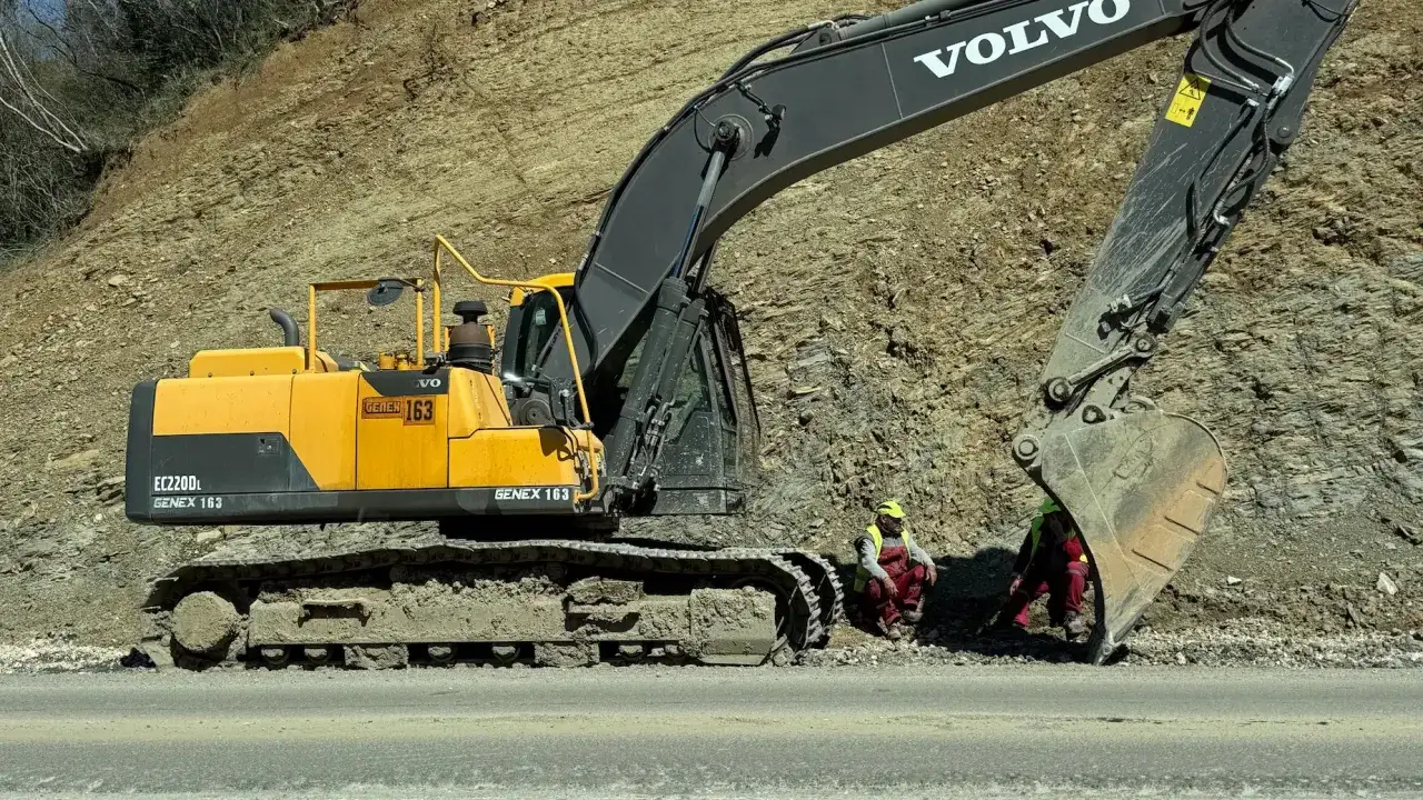 Żółta koparka gąsienicowa Volvo EC220DL. Dwie osoby w kamizelkach odblaskowych siedzą obok. Zastanawiasz się, ile kosztuje godzina pracy koparki gąsienicowej?