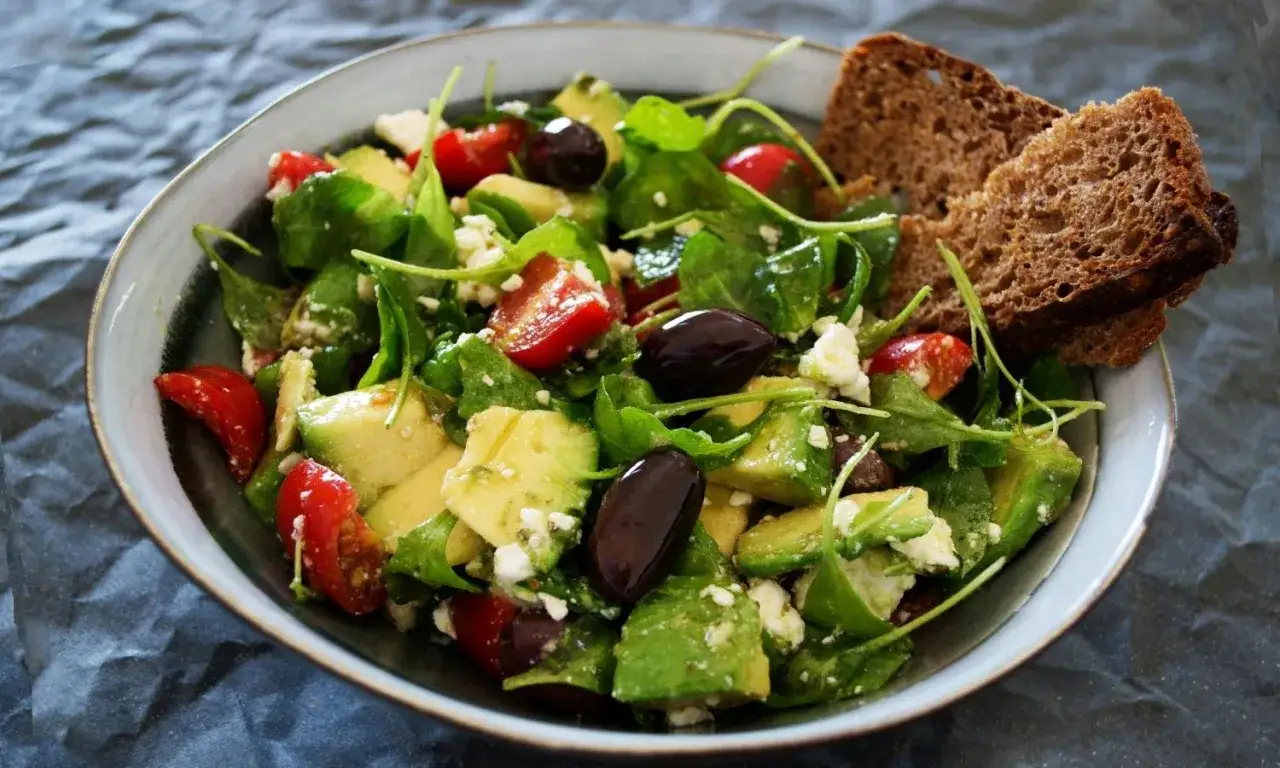 Salade color&eacute;e avec avocat, tomates, olives et feta, parfaite pour une salade pour maigrir du ventre. Accompagn&eacute;e de pain complet.