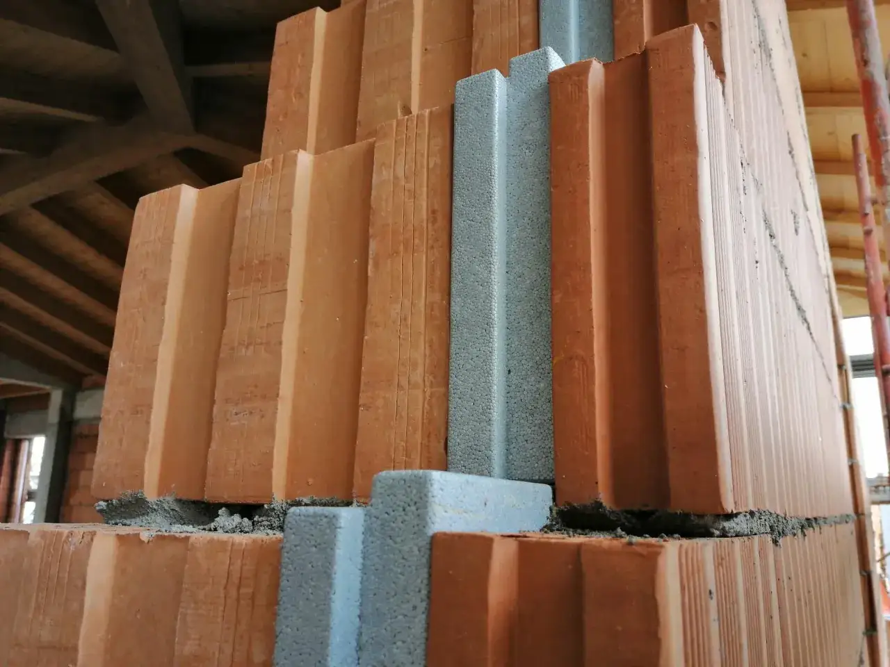 Costruzione di una parete con mattoni isolanti e inserti in polistirolo, parte di un futuro cappotto termico.