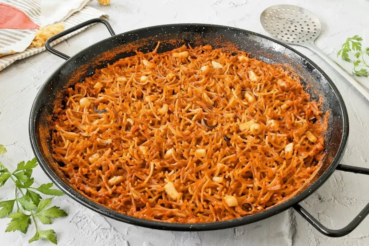 Fideu&agrave; con sepia reci&eacute;n hecha en paellera, con fideos finos y trozos de sepia, lista para servir.