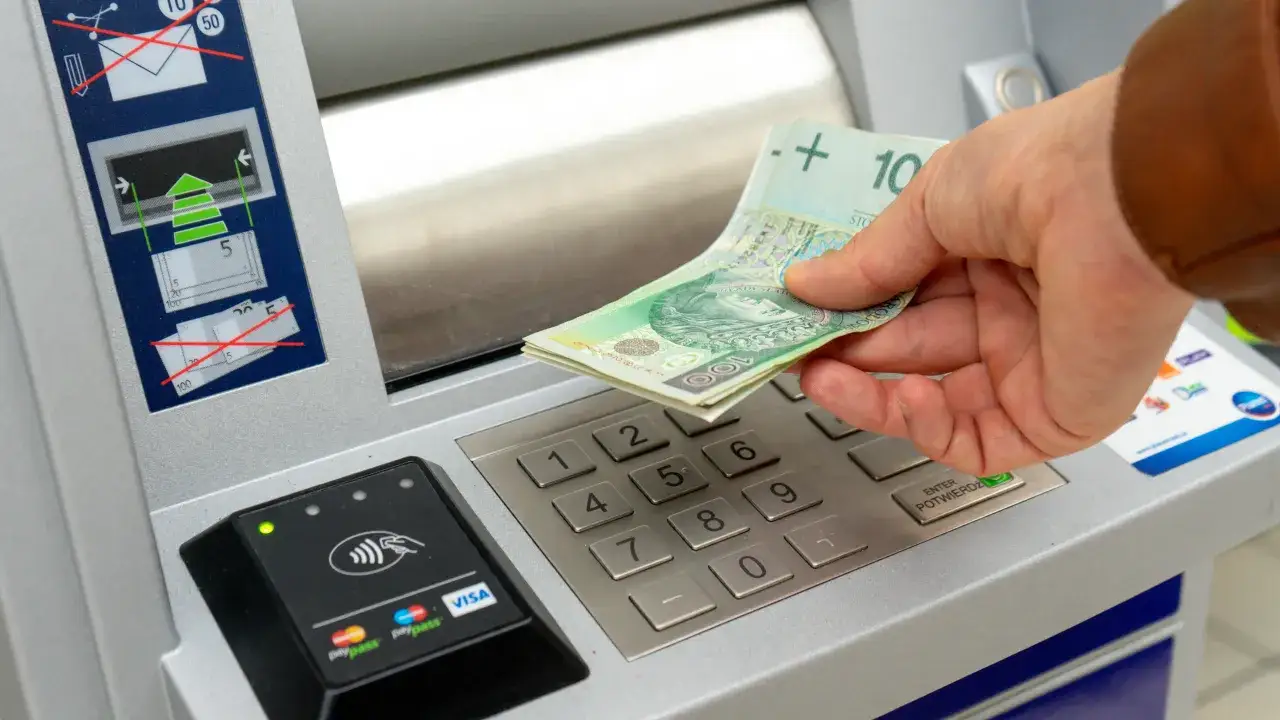Ręka wkłada banknoty do wpłatomatu mBank.