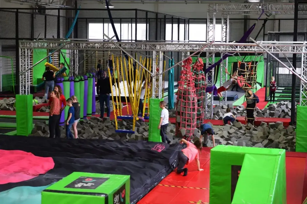 Dzieci bawią się na torze przeszk&oacute;d w Flypark Kielce, skacząc i wspinając się wśr&oacute;d piankowych kostek i lin.