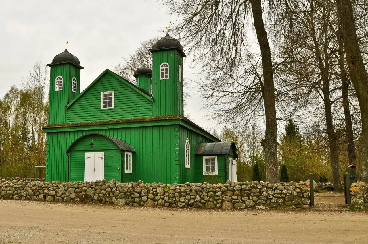 Zielona, drewniana świątynia z minaretami, przypominająca tatarską wioskę, otoczona kamiennym murem.