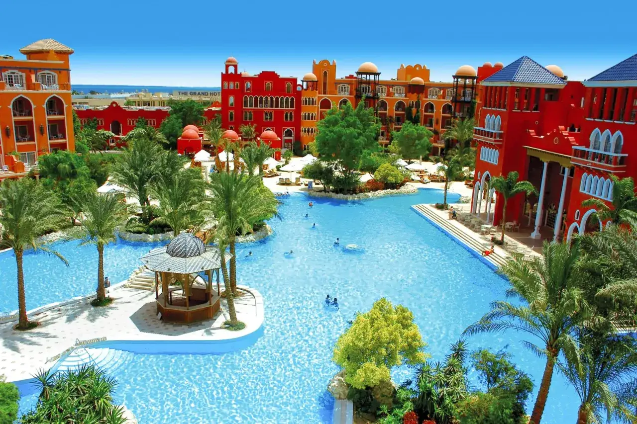 Stor pool med palmer och röda byggnader i egypten, Hurghada. En oas för avkoppling.