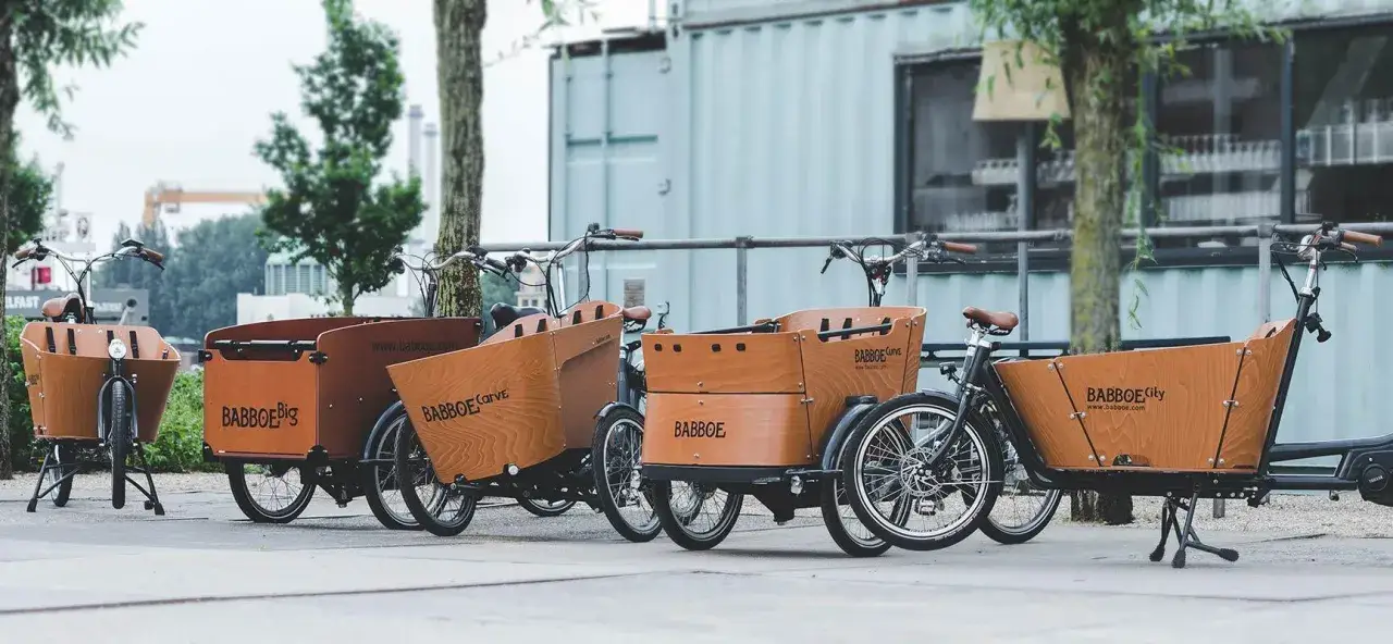 Mehrere Lastenräder mit Holzkisten stehen nebeneinander. Das Gewicht eines solchen Lastenrads ist beachtlich, aber für den Transport von Kindern oder Einkäufen ideal.