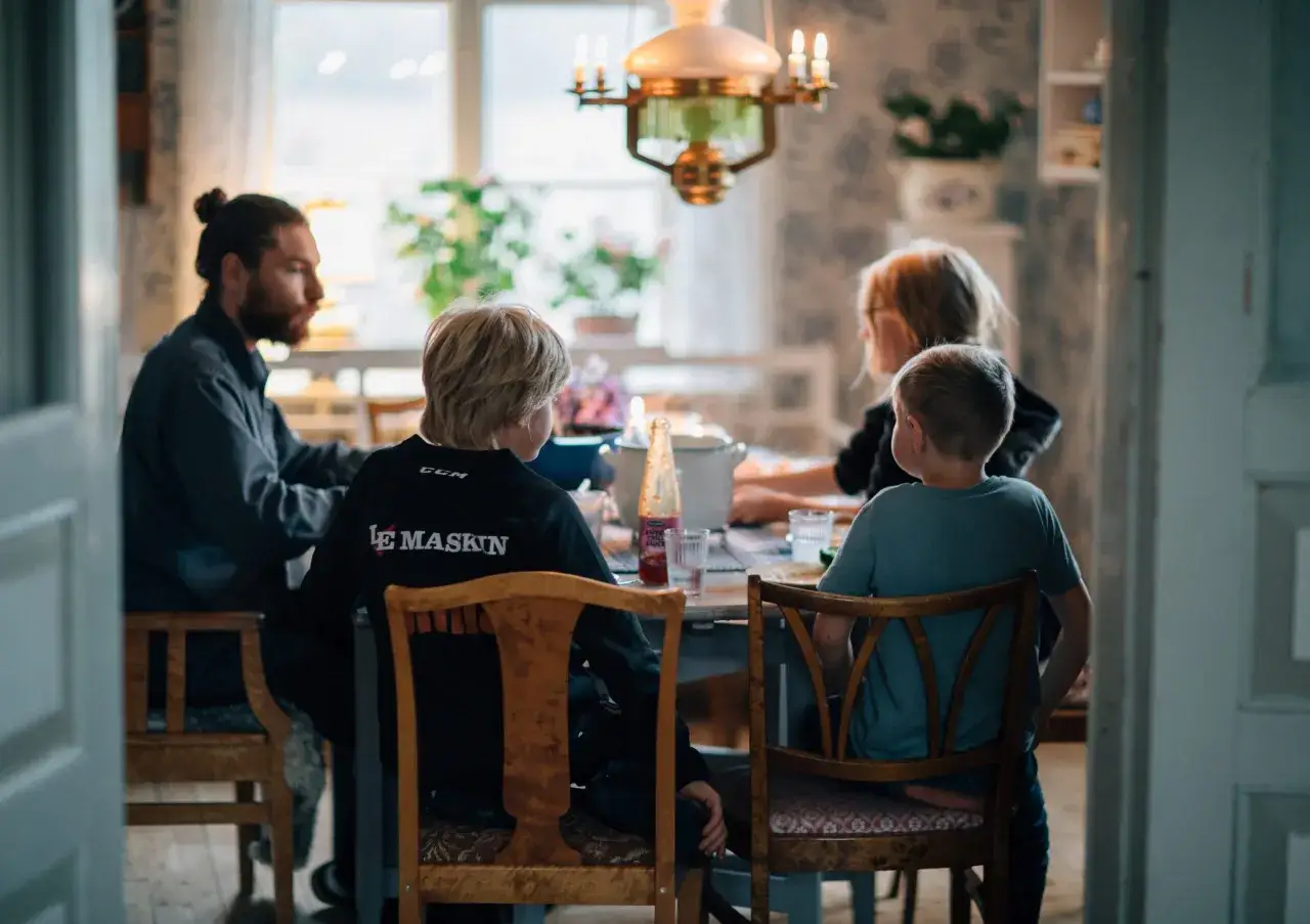 Familjen samlad runt bordet, kanske diskuterar de djupa fr&aring;gor under middagen. En pappa med h&auml;stsvans, tv&aring; pojkar och en kvinna.