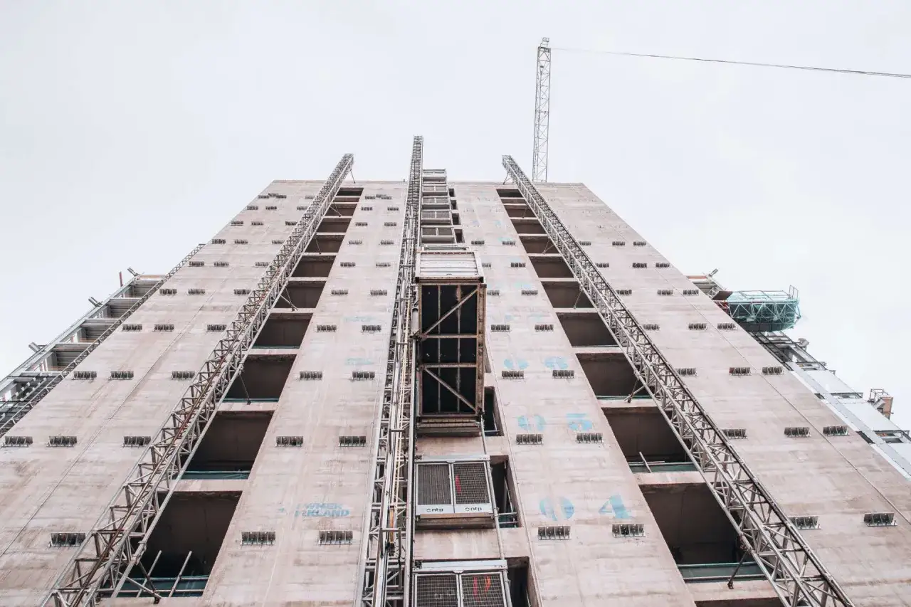 Grue et échafaudages sur un immeuble en construction, le chantier semble connaître un retard de livraison vefa.
