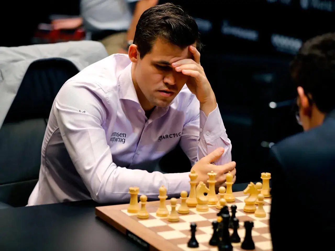 Magnus Carlsen, jeden z najlepsi szachiści w historii, zamyślony nad szachownicą.