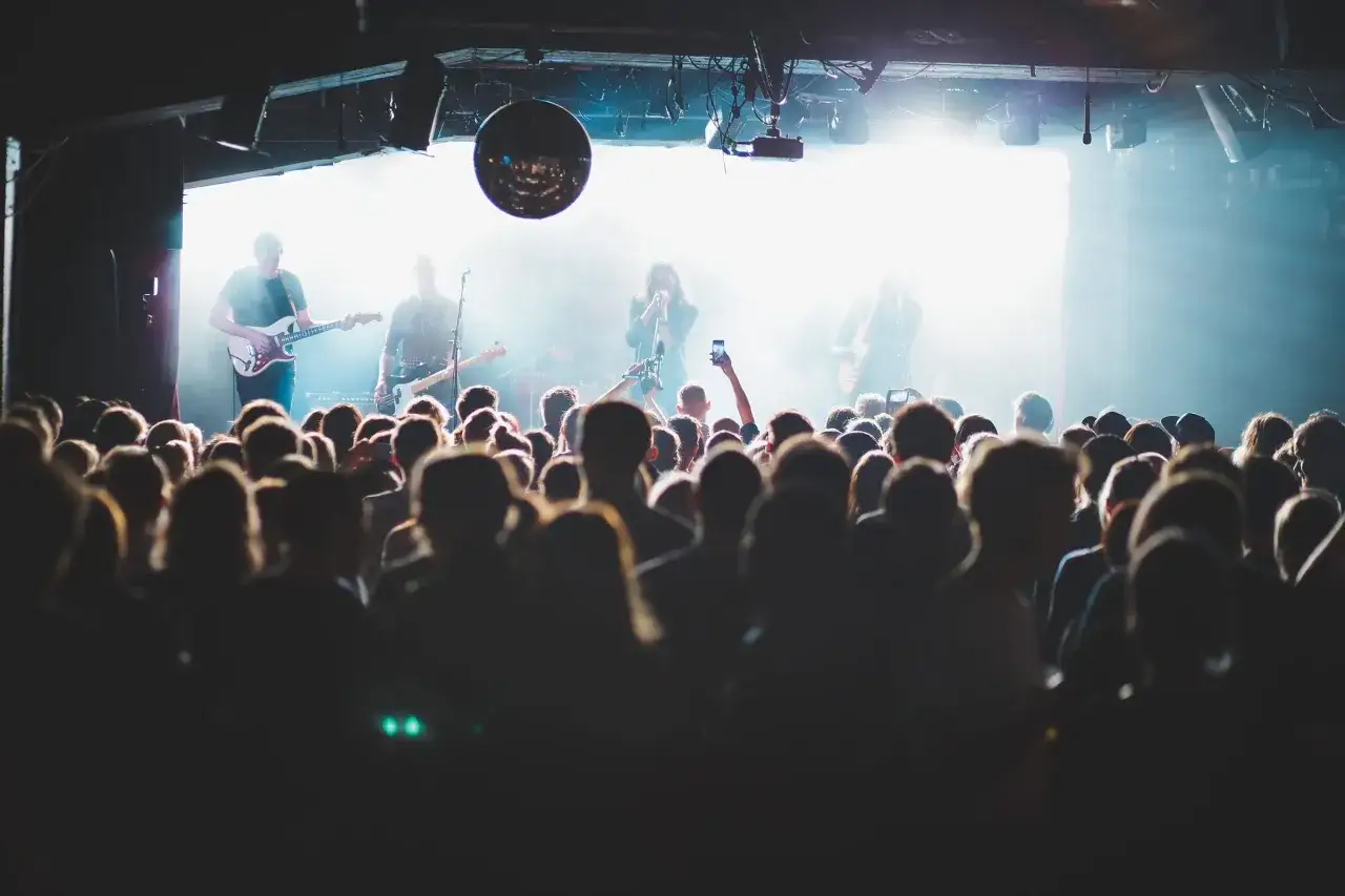 Publik njuter av en konsert i Stockholm idag. Bandet spelar på scenen med starkt ljus och rök.