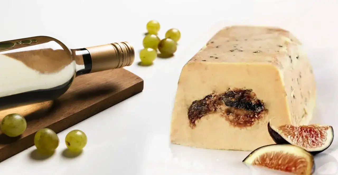 Bouteille de vin blanc &agrave; c&ocirc;t&eacute; d'un foie gras aux figues, avec des raisins verts et des quartiers de figues. Un d&eacute;lice pour les amateurs d'alcool et de foie gras.