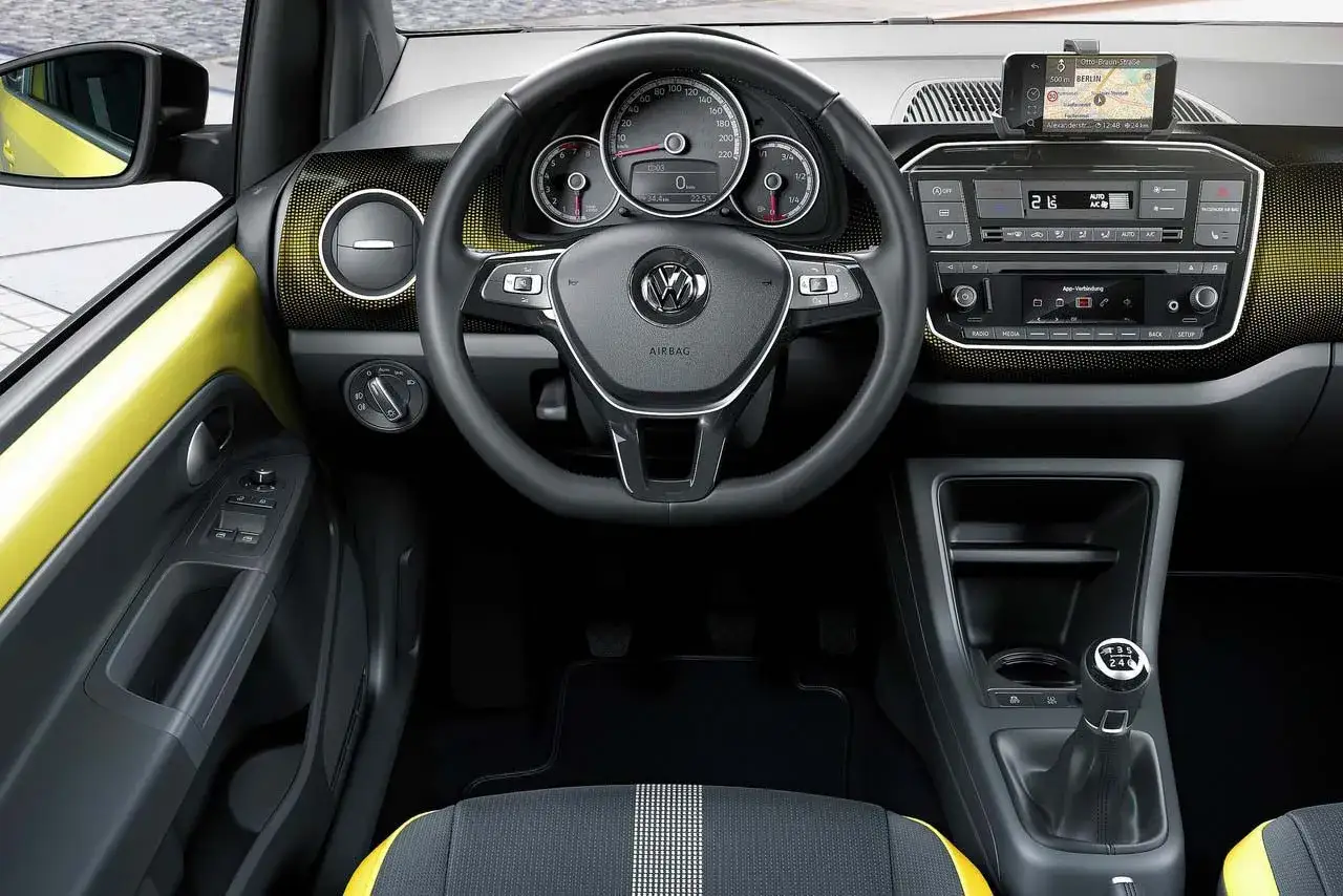 Wnętrze Volkswagen up! z żółtymi akcentami. Widoczna kierownica, deska rozdzielcza z nawigacją i panelem radia, dźwignia zmiany biegów.