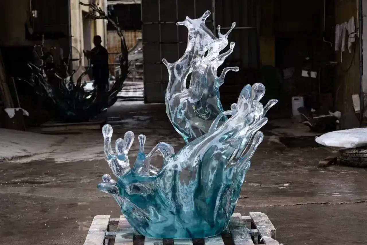 Scultura di resina trasparente che imita uno schizzo d'acqua, con gocce e spruzzi cristallizzati. La resina &egrave; un materiale versatile per creare effetti realistici.