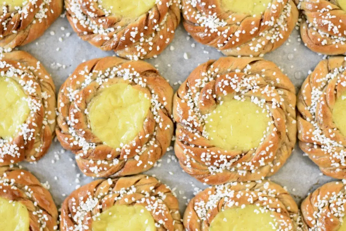 En rad gyllene bullar med vaniljkräm i mitten, strösslade med pärlsocker. En riktig desire bulle för fikat.