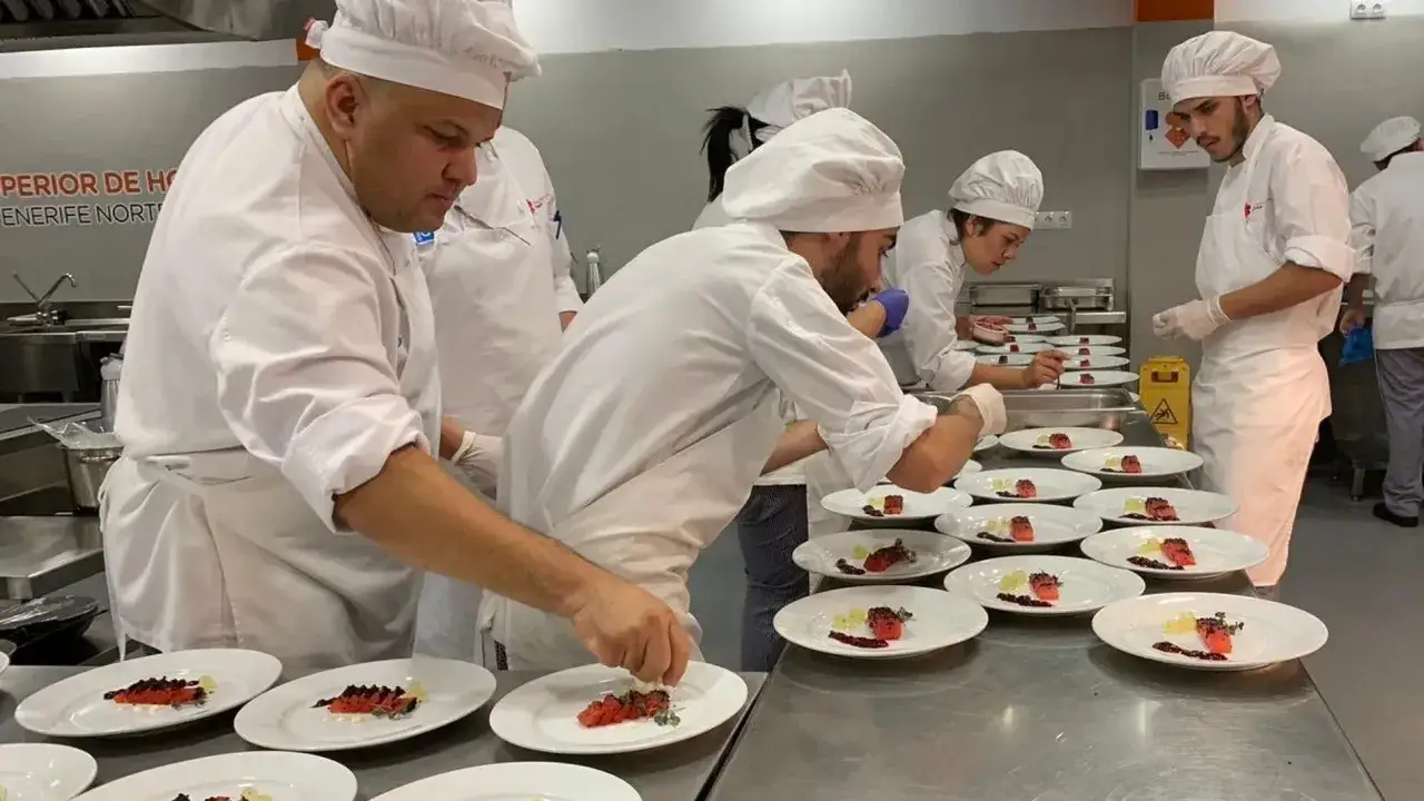 Varios chefs en uniforme blanco preparan platos de salmón en una cocina profesional. Cada chef chef añade el toque final a su obra culinaria.