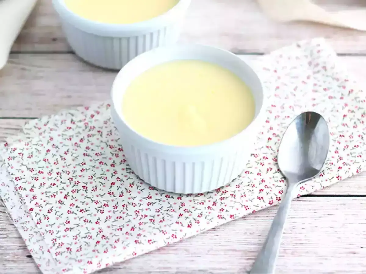 Deux ramequins de crème onctueuse, des oeufs au lait parfaits, sur une serviette fleurie. Une cuillère attend patiemment.