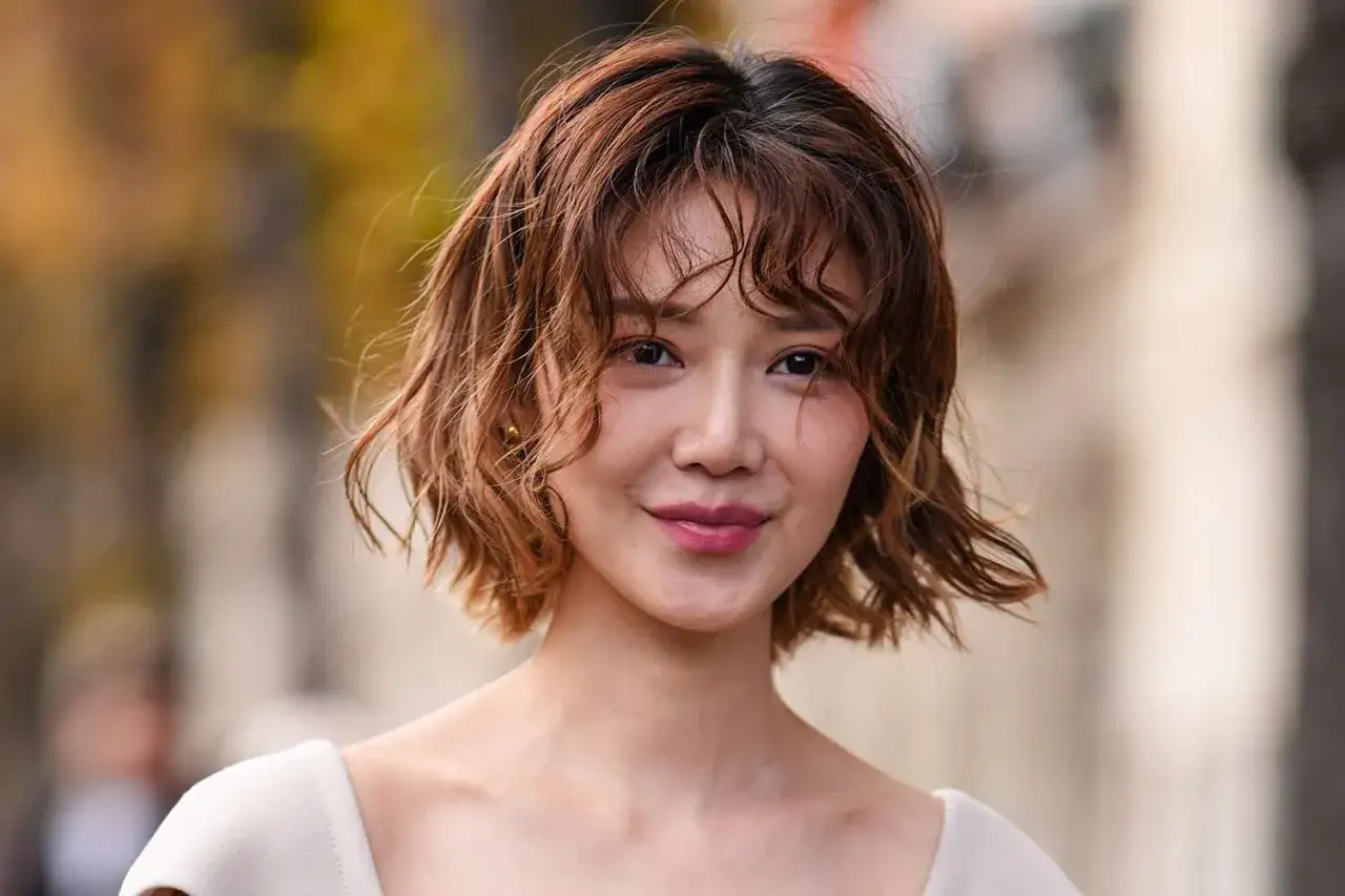 Mujer sonr&iacute;e con un moderno corte pelo bob ondulado y casta&ntilde;o.