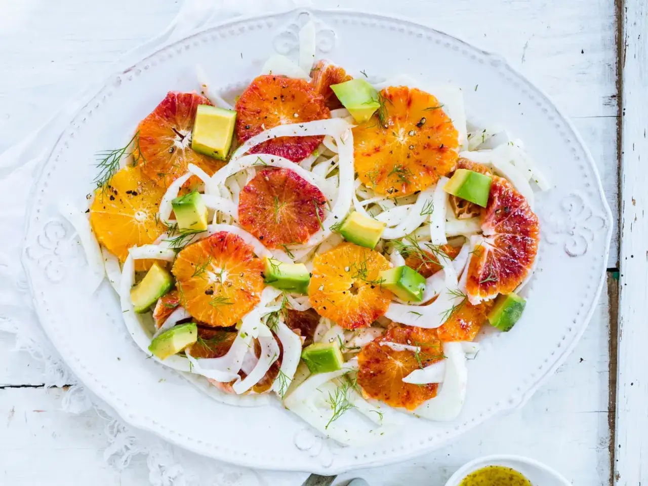 Erfrischender Fenchel-Orangen-Salat mit Avocado und Dill. Bunte Scheiben von Blutorangen und Orangen liegen auf hauchdünnem Fenchel.