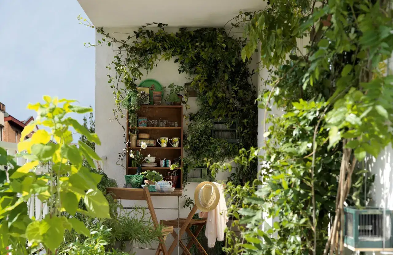 Un balcon verdoyant, une étagère en bois remplie d'objets charmants, une théière et des tasses pour un moment de détente. Une belle deco balcon.
