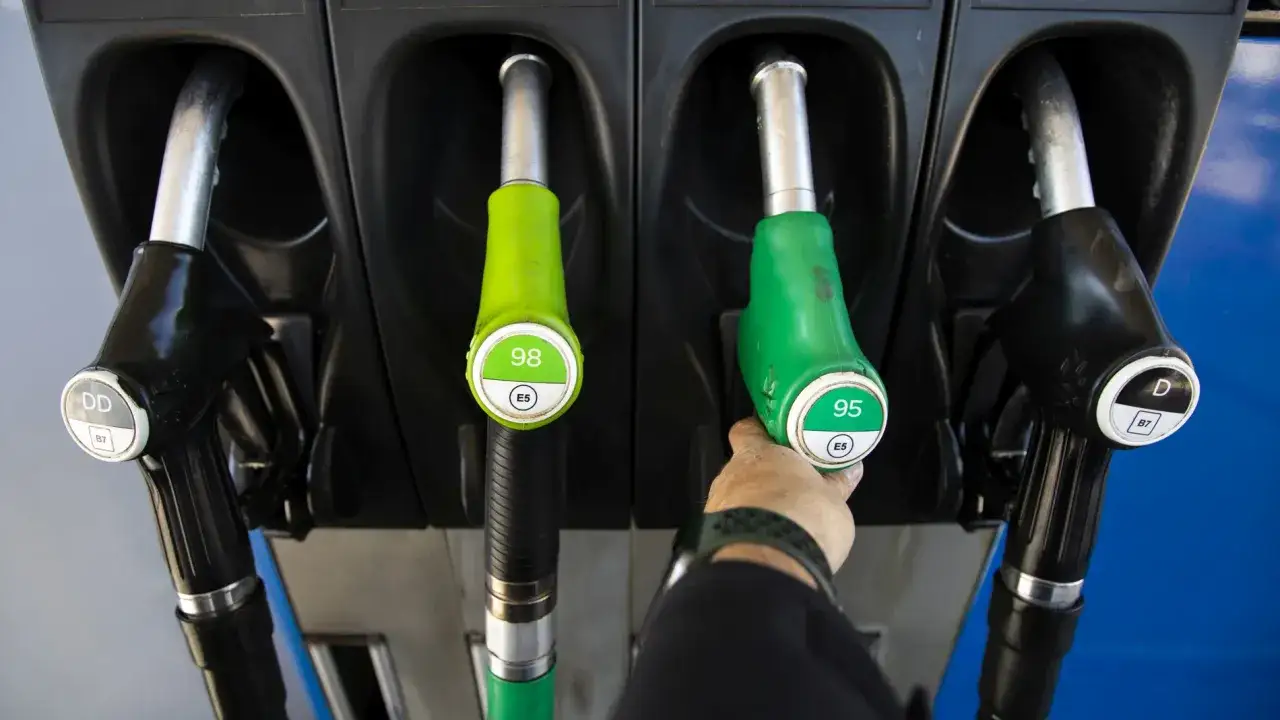 Mangueras de gasolina y diésel en una gasolinera. La mano elige entre 95 y 98 octanos, comparando el **precio gasolina vs diesel**.