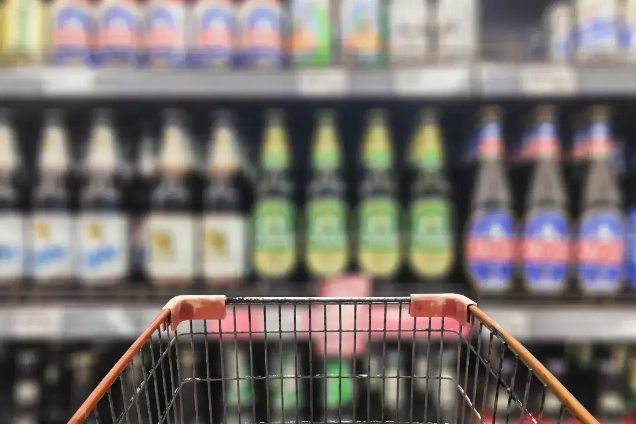 Wózek sklepowy przed półką z butelkami piwa. Szukam nowych kraftowych smaków.