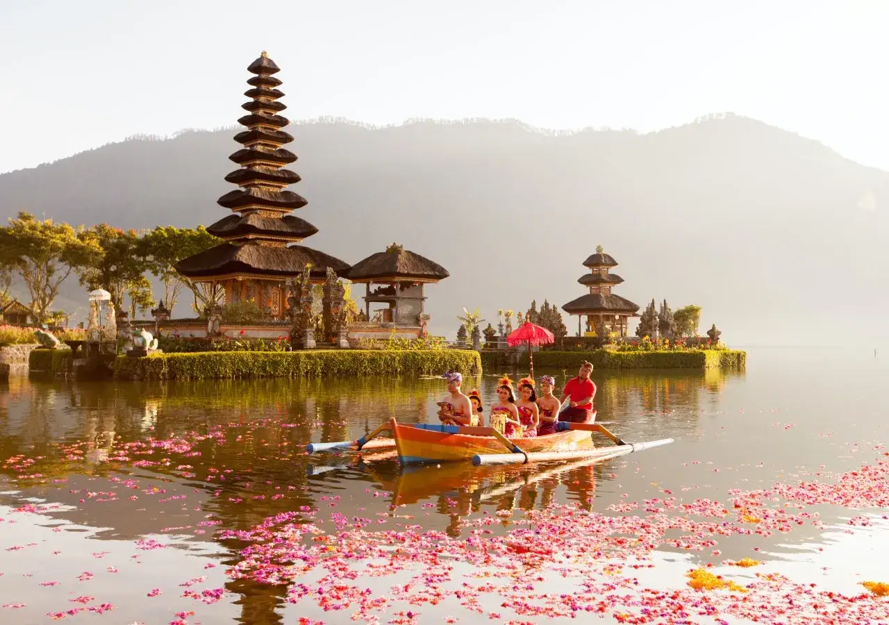 Barca con bailarines tradicionales navega en lago con templo Pura Ulun Danu Bratan. ¡Una experiencia que ver qué hacer en Bali!