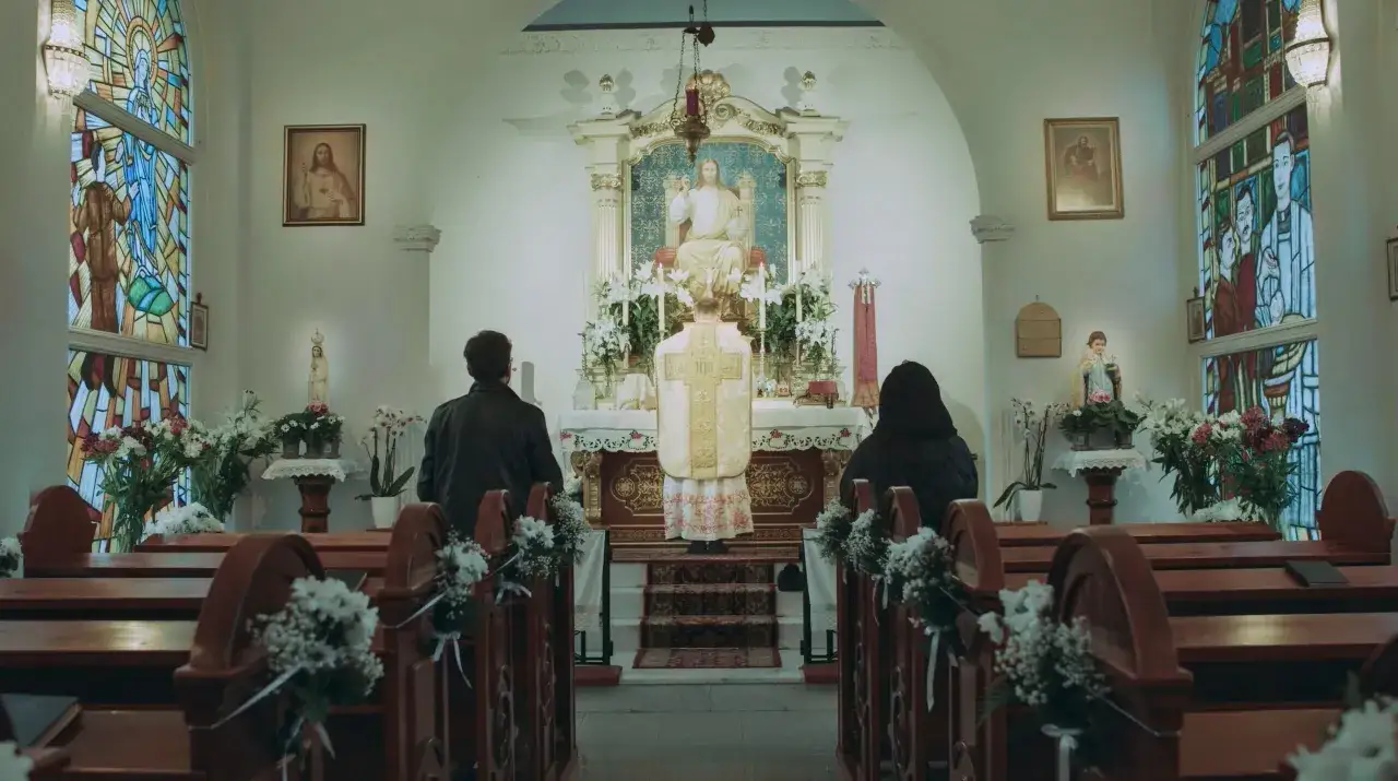 Uroczysta msza trydencka w kościele. Kapłan w ornacie odprawia nabożeństwo przed ołtarzem, a wierni klęczą w ławkach.