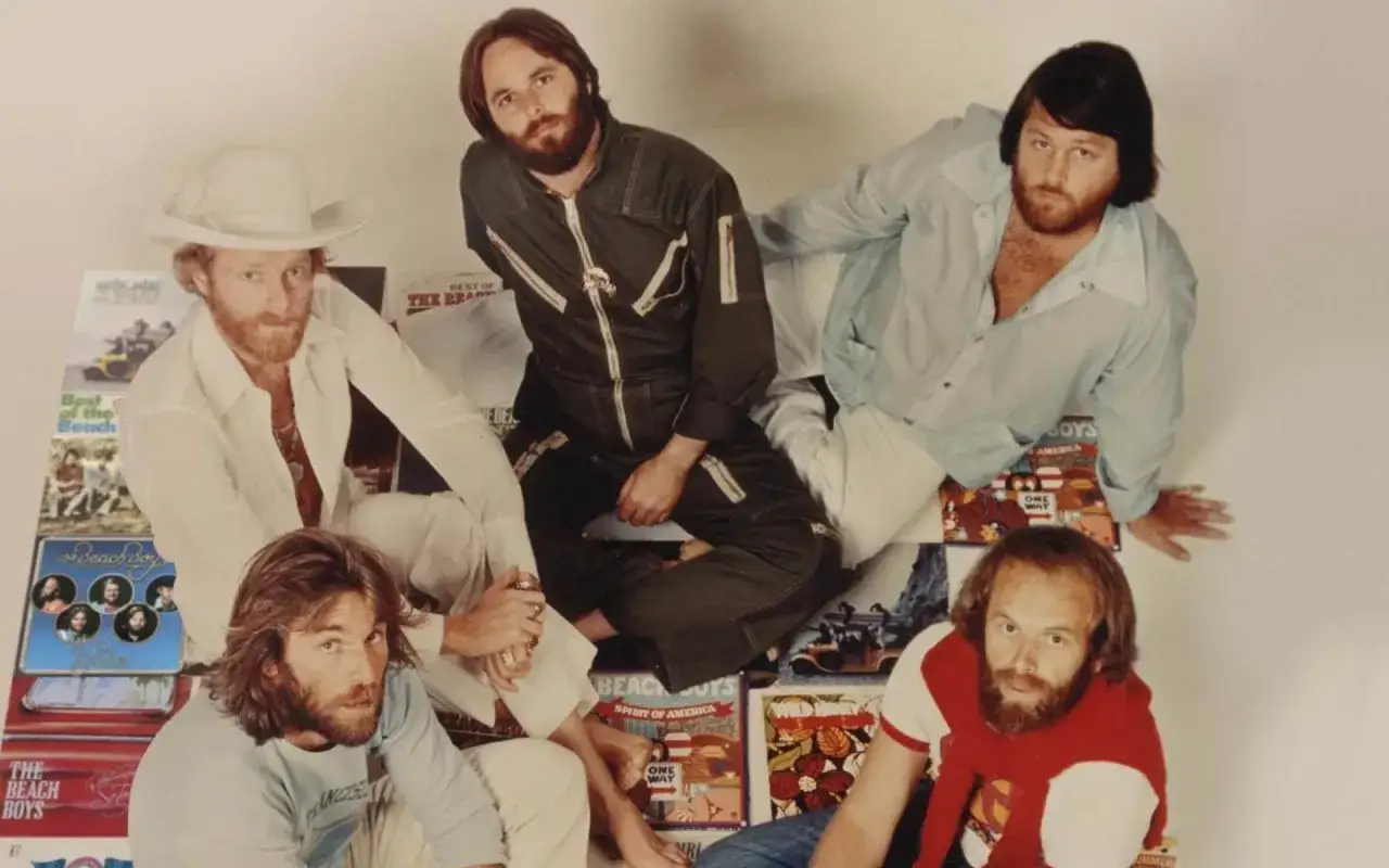 Medlemmar av The Beach Boys poserar bland sina skivomslag.