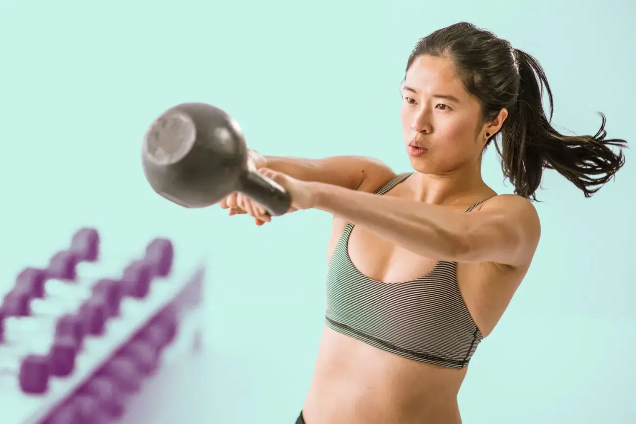 En kvinna utf&ouml;r en kettlebell swing med fokus.