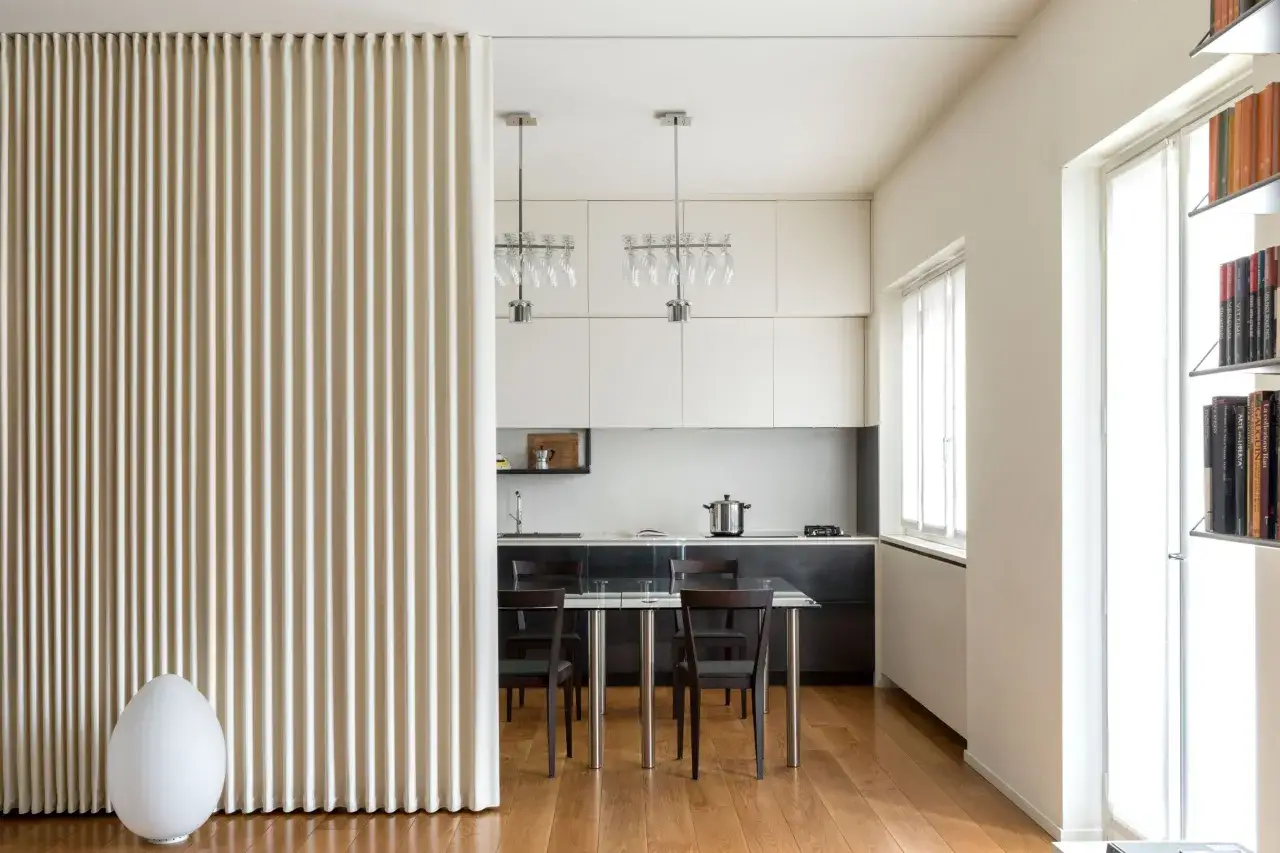 Un pannello ondulato beige divide elegantemente lo spazio, creando un modo moderno per dividere una stanza senza opere murarie.